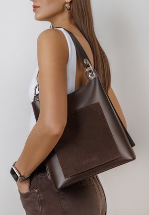 Brązowa skórzana torebka z zamszowym akcentem. Posiada srebrne elementy metalowe oraz strukturalny design. Torebka ma krótki pasek na ramię.