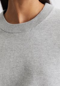 Szary sweatshirt z prążkowanym dekoltem, wykonany z miękkiej, teksturowanej tkaniny o gładkim wykończeniu i minimalnych detalach.