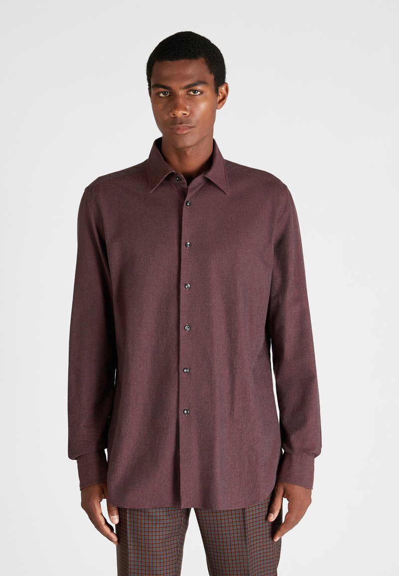 Bordeaux lange mouw shirt gemaakt van textuurstof met een knoopsluiting aan de voorkant, klassieke kraag en zwarte knopen; gedragen met geruite broek.