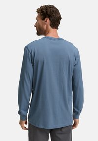 Lange mouwen shirt van zacht, lichtblauw stof. Heeft een ronde hals, een relaxte pasvorm en ribgebreide manchetten. Gladde textuur, minimale stikdetails.