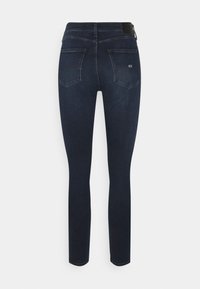 Tmavě modré úzké džíny z denimu s vysokým páskem, dvěma zadními kapsami a hladkou texturou s minimálním viditelným šitím.