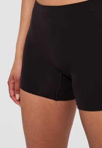 Svarta bomullsstretchshorts med midje som sitter åt och slät yta. Har en längd som når mitt på låret och sömlös design för komfort.