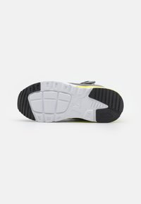 Black and white sneaker sole, featuring textured rubber for grip, highlighted by a distinct yellow accent along the side.