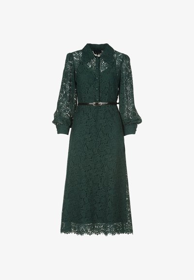 Dunkelgrünes Spitzenkleid mit einem Kragen, langen Puffärmeln und einem taillierten Gürtel. Der Saum ist gewellt, was die Spitzenstruktur betont.