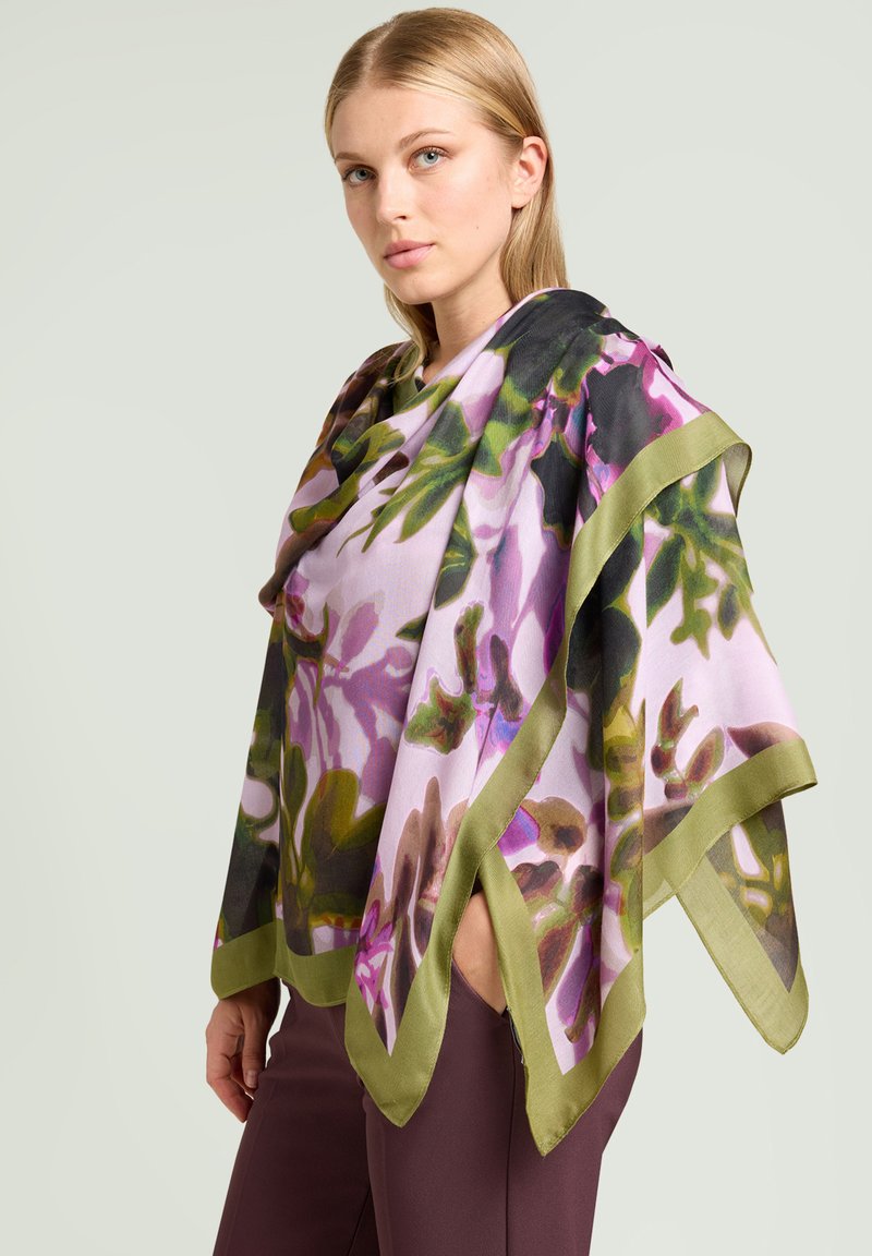 Poncho ligero de seda en rosa pastel, con un colorido patrón floral y borde en verde oliva. Forma triangular con tela fluida.