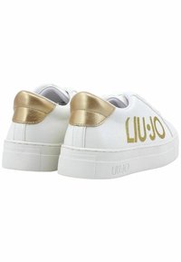 Sneaker bianche con una finitura in pelle liscia e dettagli metallici dorati sul tallone. Presenta una suola in gomma texturizzata. Logo dorato sul lato.