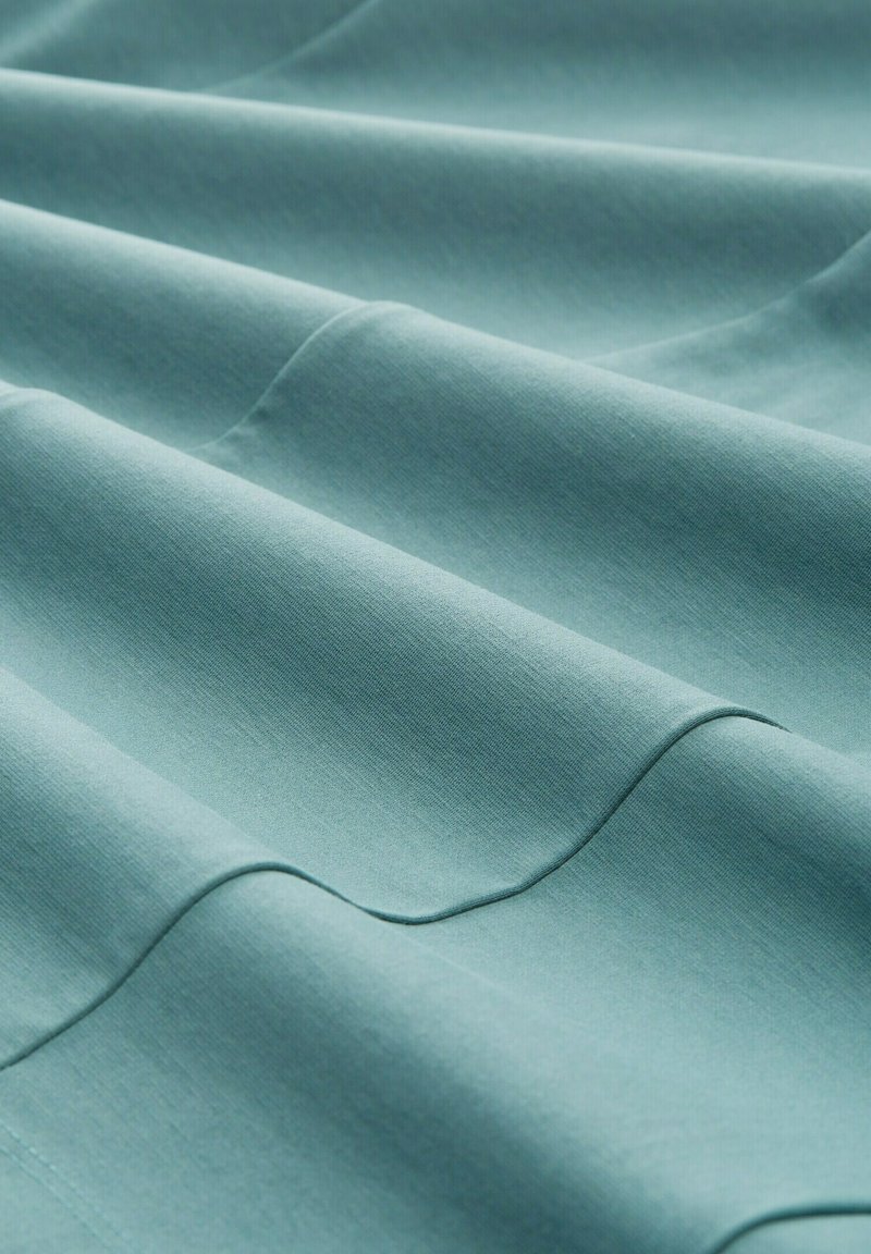 Lichtgroenblauw stof met een gladde textuur, met subtiele plooien en een gelijkmatig oppervlak. Het materiaal lijkt zacht en licht van gewicht.