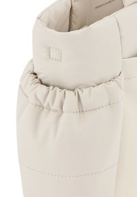 Puffer-takki kaulus vaaleassa beige-kankaassa, jossa on poimuttunut muotoilu, sileä pinta ja näkyvät ompelutiedot.