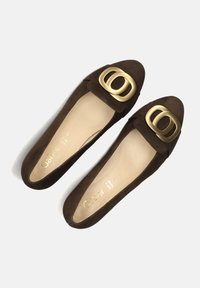 Donkerbruine suède damesloafers met grote gouden ovale gespen aan de voorkant en beige binnenzolen met merktekst.