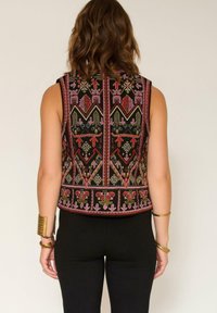Gilet brodé avec une base en tissu noir et des motifs complexes en rouge, rose et or. Design sans manches avec un ourlet arrondi.
