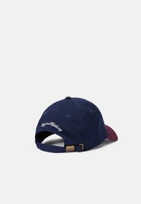 Marineblå bomuldsbaseballcap med maroon skygge, med hvid "Original Clothing" broderi på bagsiden og justerbar rem.