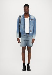 Denim jaka ar gradienta zila mazgāšanu, ar priekšējiem kabatām. Balts topiņš, džinsu šorti un melni apavi. Vienkārša crossbody soma.