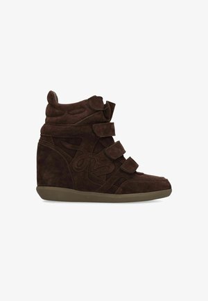 Sneaker zeppa in camoscio marrone scuro con tre cinturini in velcro regolabili e colletto imbottito alla caviglia su suola piatta in gomma.