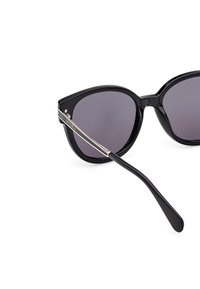 Gafas de sol negras tipo cat-eye con lentes degradados, que cuentan con un armazón de plástico brillante y elegantes acentos plateados en las patillas.