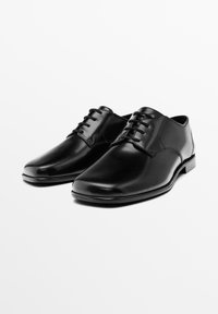 Chaussures habillées noires en cuir avec une finition lisse, à bout rond et six œillets pour les lacets. Présentent un léger éclat et un talon bas.