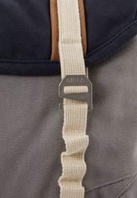 Kangaskott, millel on tumesinine ülemine osa, pruuni nahast aksent ja beež rihm. Omab metallist klambrit, millel on graveeritud "MELA". Tekstureeritud hall kangas alus.