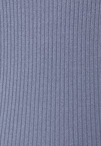 Tissu côtelé de teinte bleu clair avec de fines lignes verticales, présentant une texture douce et une élasticité pour le confort.