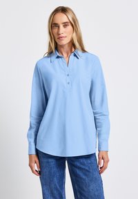 Camicia a maniche lunghe blu chiaro con colletto, dotata di patta con bottoni e orlo curvo. Tessuto morbido con una texture liscia.