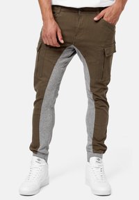 Cargo joggers featuring a brown cotton blend front and gray sweatshirt material on the sides, with multiple pockets and ankle cuffs.