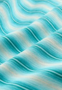 Tissu doux avec des plis ondulés dans des nuances de bleu, turquoise et blanc en rayures horizontales, montrant la texture et une fluidité douce.