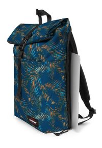 Plecak z rolowanym zamknięciem, wykonany z niebieskiego wzorzystego materiału, z czarnymi paskami i boczną kieszenią. Posiada naszywkę z logo oraz elegancki design do przenoszenia przedmiotów.