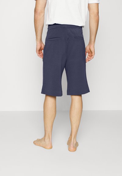 Calções azul-marinho feitos de um tecido leve, com um corte reto, comprimento até à metade da coxa e dois bolsos nas costas.