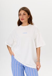 Witte oversized t-shirt met korte mouwen, voorzien van blauwe "MIRONS" tekst op de voorkant. Gladde stof, comfortabele pasvorm en ronde hals.