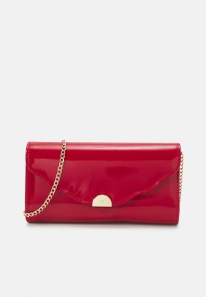 Bolso de mano rojo brillante con solapa con borde ondulado y cadena dorada, cerrado con un pequeño cierre dorado en forma de medio círculo.