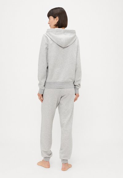 Pelēka kapuces džemperis un saskaņotas sporta bikses no mīksta kokvilnas maisījuma. Iezīmējas ar ribotām piedurknēm un brīvu piegriezumu.