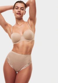 Beige sömlös behå med bygel och tunna band, kombinerad med högmidjade trosor med spetskant. Mjuk tygstruktur.