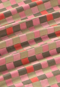 Multifarvet mønsterstof med firkanter i pink, rød, brun og beige nuancer. Blød tekstur med en glat overflade.
