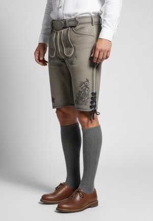 Grå traditionella shorts med blommönster, sidoförsedda snörningar och ett midjeband med en dekorativ spänne. Bärs med grå knähöga strumpor och bruna skor.