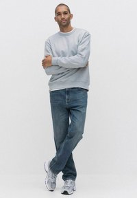 Harmaa huppari, jossa on ribbireunus, siniset farkut ja harmaat lenkkarit. Asu on rento ja pehmeä kangastus.