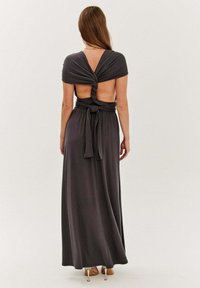 Maxi šaty s krátkymi, zavinutými rukávmi; vyrobené zo sivej látky. Majú uzlový dizajn na chrbte a otvorený chrbát s viazaným pásom.