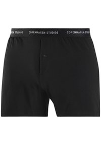 Sorte bomull boksershorts med knappåpning og elastisk midjebånd med teksten "COPENHAGEN STUDIOS" i hvitt. Glatt tekstur.