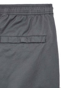 Grå tekstilshorts med elastisk midjebånd og en baklomme med horisontal klaff. Materialet fremstår glatt med en matt overflate.