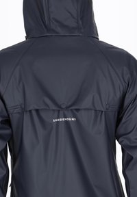 Navy waterproof jacket with a hood, featuring a smooth texture, two buttons on the back, and "SWEDEMOUNT" logo in white.
