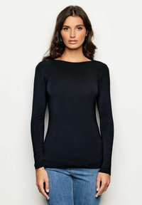 Maglietta nera a maniche lunghe realizzata in un tessuto liscio con scollatura rotonda, abbinata a jeans in denim blu. Vestibilità adatta con una morbida texture.