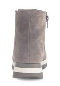 Bottine en suède gris avec une fermeture éclair sur le côté, surface texturée, semelle rembourrée et bande d'accent blanc contrastant sur le talon.