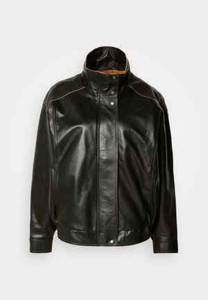 Black leather jacket featuring a high collar, snap button closure, and contrasting tan stitching. Smooth texture with a slightly oversized fit.