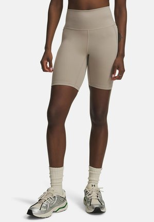 Beige high-waisted fietsshorts van rekbare stof, met een gladde textuur en eenvoudige stiksels, gecombineerd met sportieve sneakers en sokken.