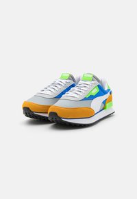 Chaussures de sport grises, bleues et orange avec des lacets blancs ; accents verts et design sportif ; présentent un daim texturé et une semelle extérieure en caoutchouc.