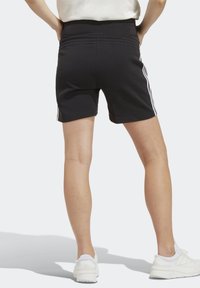 Svarta träningsshorts med hög midja, med tre vita ränder längs sidorna. Bakifrån framhäver en slät textur.