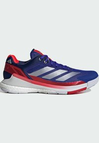 Blue athletic shoe with silver stripes and red accents. Features a mesh upper, padded collar, and textured white outsole for grip.