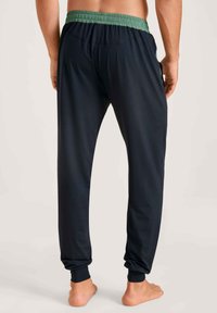 Navy joggerbroeken met een groene elastische tailleband, voorzien van zijzakken en taps toelopende boorden. Gemaakt van een soepele, lichtgewicht stof.