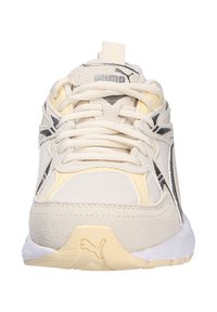 Puma sneakers featuring a light beige upper with yellow accents, mesh and suede materials, lace-up design, and a textured white sole.