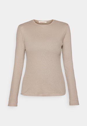 Beżowa, długorękawowa bluzka z prążkowanej tkaniny, z okrągłym dekoltem i dopasowanym krojem. Posiada małą metkę z materiału u dołu, wykonana z miękkiego materiału.