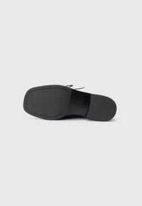 Black leather shoe sole with a smooth finish, featuring a rectangular shape and subtle stitching along the edge. No visible patterns.