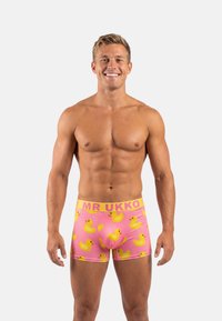 Roze boxershorts met gele rubberen eendjespatronen en een contrasterende gele tailleband met de tekst "MR UKKO". Zacht, rekbaar stof.