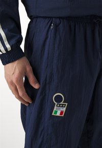 Námornícky športový komplet s elastickým pásom, zipsom na vrecku a výraznou vyšitou nášivkou s talianskou vlajkou a detailným textom.